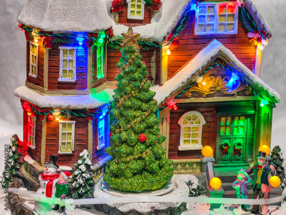 Naklejka premium Christmas Village Miniature House with Colorful LED Lights, Glitter Tree and Snowman Figurines for Holiday Decoration Background 