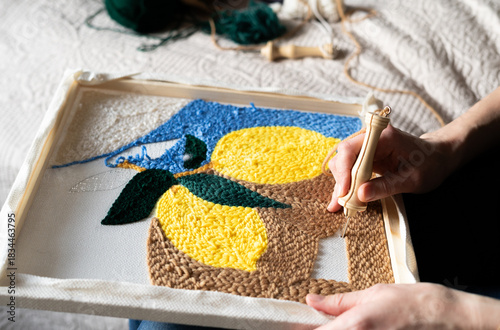 Crafting a rug design with lemons and blue elements in a cozy indoor setting during daytime. punch needle