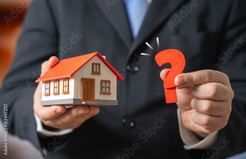 Fotografie A house and a question mark held by a man in a suit