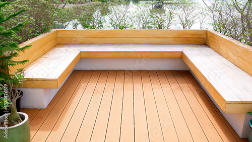 Modern wooden deck seating area and built-in bench in a minimalist outdoor garden with natural light and surrounding greenery with lake view