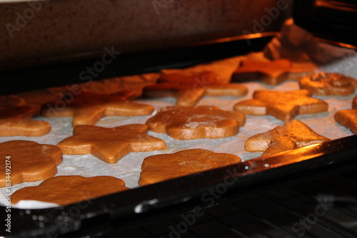 Baking gingerbread cookies in an oven on a tray lined with parchment paper near the holiday season