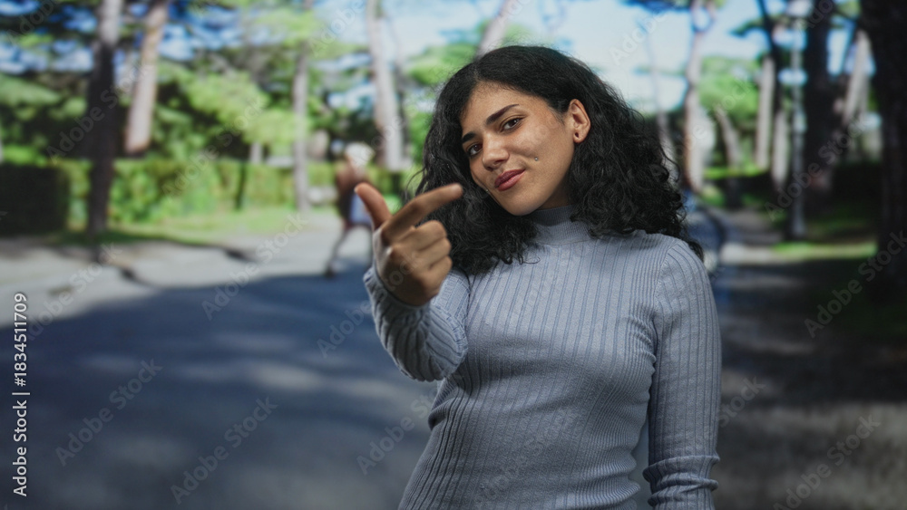 Fototapeta premium Woman points finger at camera on street showing nose piercing and turtleneck; casual direct confidence.
