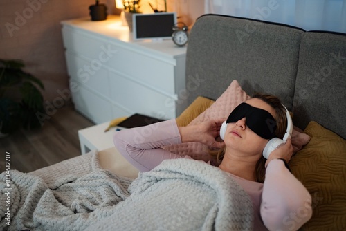 Woman wearing sleep mask and headphones listening to relaxing music