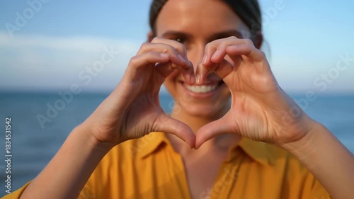 A young woman makes a heart shape with her hands, smiling joyfully Stock Video