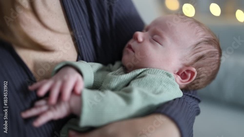 A woman is caring for her baby. The mother is rocking the baby in her arms. The newborn is sleeping. A close-up of the baby in the woman's arms.