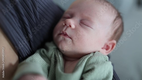 A woman is caring for her baby. The mother is rocking the baby in her arms. The newborn is sleeping. A close-up of the baby in the woman's arms.