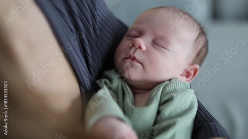 A woman is caring for her baby. The mother is rocking the baby in her arms. The newborn is sleeping. A close-up of the baby in the woman's arms.