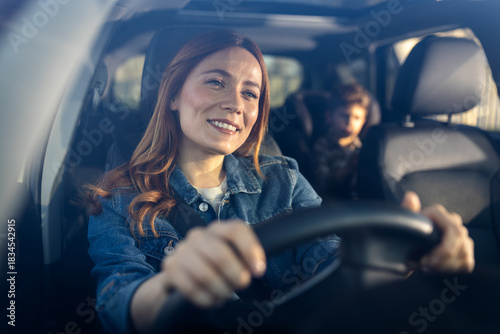 Woman driving car with child in backseat on a sunny day