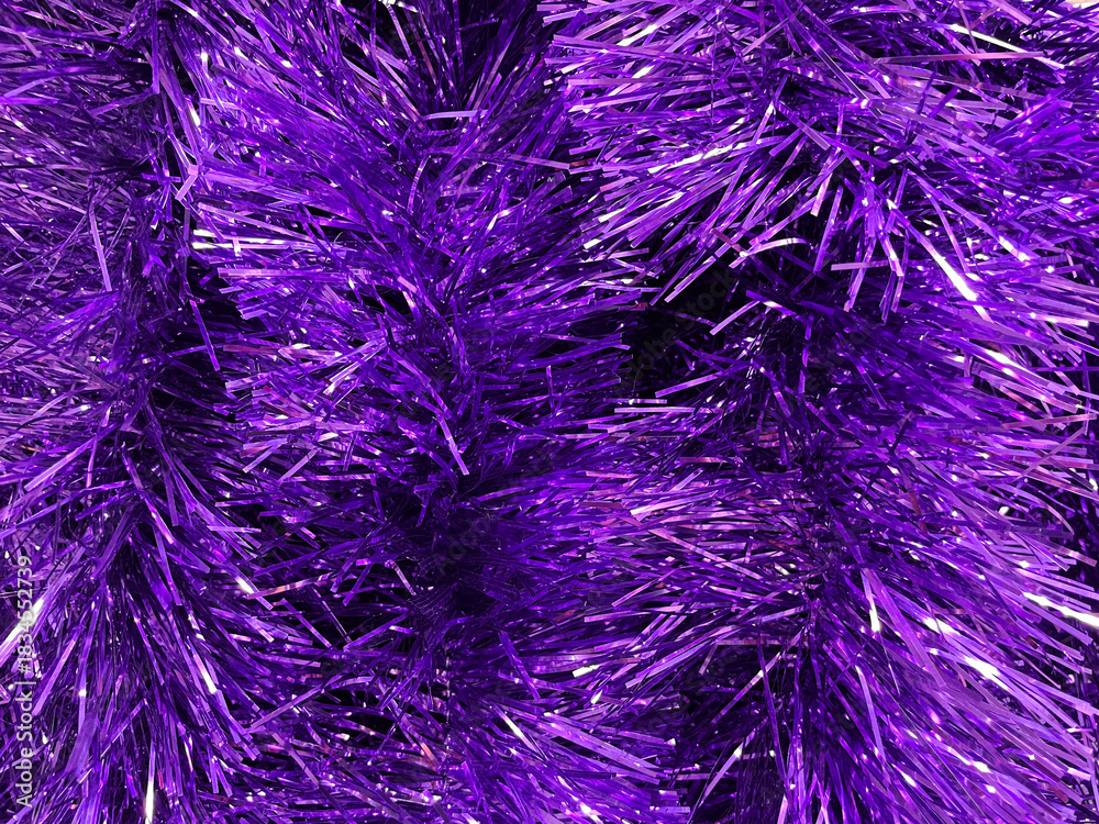 Obraz premium A dense texture of bright purple tinsel filling the frame. A concept of festive decoration, color vibrancy and holiday atmosphere.