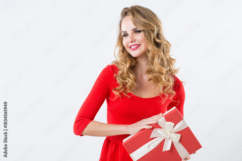 Fototapeta premium Charming blonde holding gift box with bow in hands smiling isolated on white.