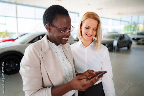 Car salesperson showing customer information on mobile phone
