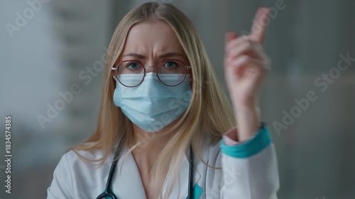Web cam view angry Caucasian doctor woman in medical face mask shaking finger no disagree disapprove fail talking looking at camera practitioner female nurse girl talk medicine health problem conflict