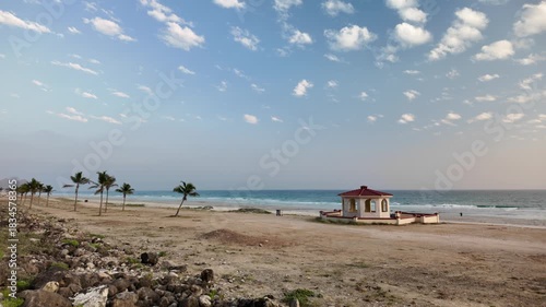 Mughsayl Beach close to Salalah, Dhofar, Oman, showcases a beautiful coastal landscape with blue skies, calm sea, and distant mountains in dry season.