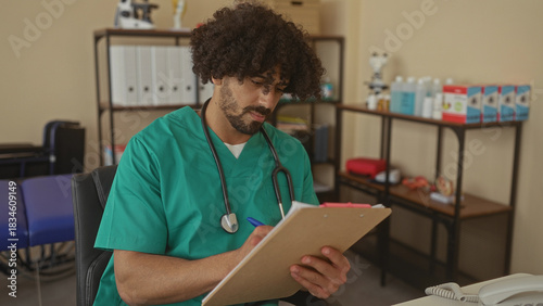 Foto Man doctor with stethoscope writing on clipboard in clinic building, seated at desk and checking notes; focused care