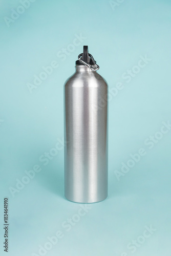 The silver water bottle stands out elegantly against the bright blue background