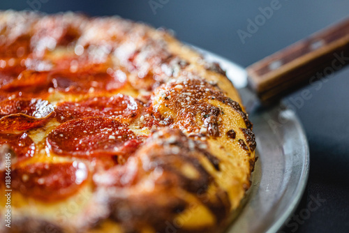 Schilderij op canvas Close up of the crust on a pepperoni pizza served at a modern pizza restaurant