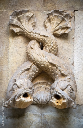 Old historic water font formed from two fishes with their tails entwined in Lisbon, Portugal