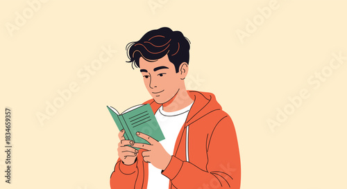 Young man wearing an orange hoodie standing and smiling contentedly as he reads a small green book with great interest.