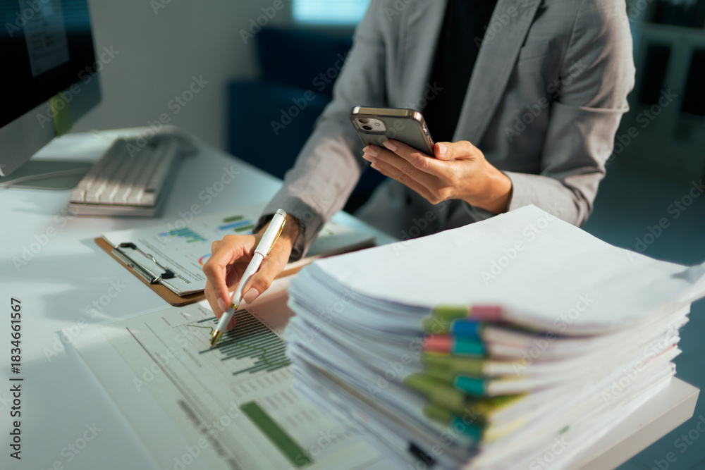 Fototapeta premium Businesswoman multitasking with smartphone analyzing financial data