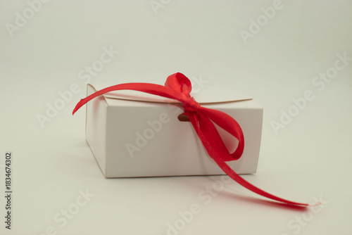 Minimalist white gift box with red ribbon