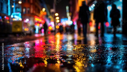 Night street scene with wet pavement reflecting vibrant city lights and blurred pedestrian silhouettes, creating a dynamic urban atmosphere. High quality