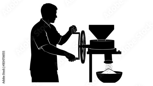 Silhouette of a person operating a manual grain mill for grinding flour