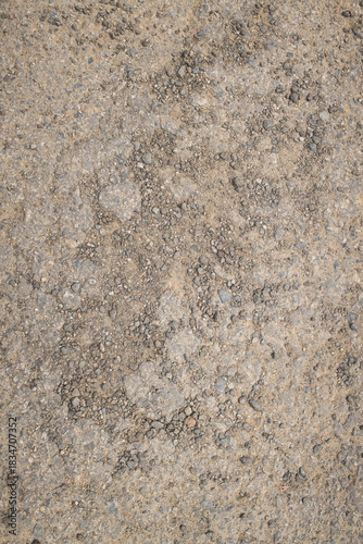 A close-up of compacted dirt mixed with small gravel and stones, showing natural earthy tones and rugged texture.