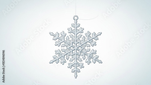 A single detailed crystalline snowflake ornament hangs suspended by a thin thread against a soft gradient light blue background representing winter
