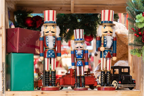 A cheerful display of tall and small nutcrackers dressed in red, white, and blue, surrounded by wrapped gifts and toy cars, capturing a warm, festive holiday scene ideal for Christmas.