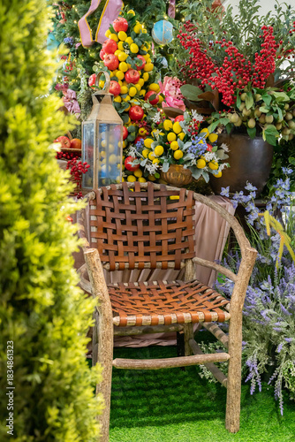 A cozy wicker garden chair is nestled among vibrant blooms, lanterns, and lush greenery, creating a charming outdoor decor scene