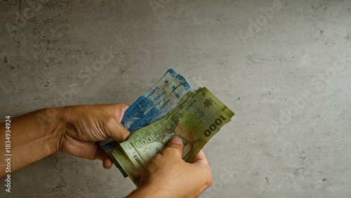 Canvastavla Hands holding chilean pesos against a concrete wall, showcasing various denomina