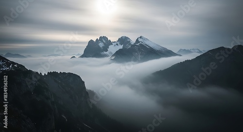 Jagged peaks emerge from clouds under a hazy sun.