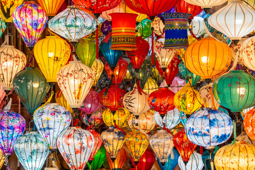 A vibrant display of traditional handmade silk lanterns hanging in the historic old town of Hoi An, Vietnam, during a local market. A symbol of Vietnamese culture, light, and tradition.