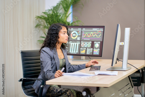 Mixed businesswoman in suit working with many monitor for analyzt data and graph for business forecast.