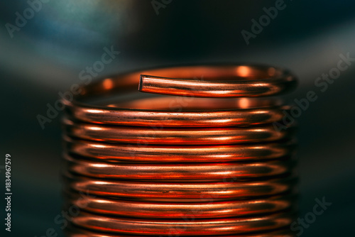 Copper wire coiled into a coil or spiral, closeup with a blurred industrial background