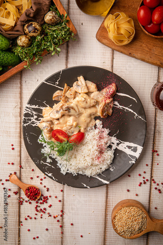 Photography Tender chicken fricassee in creamy mushroom sauce served with rice and herbs on