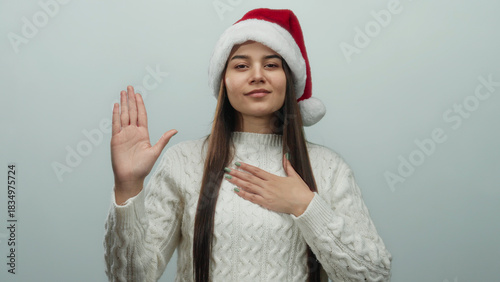 Принти на полотні Woman in santa hat and sweater pledging allegiance over white background
