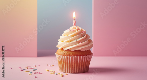 Pastel birthday cupcake with lit candle and sprinkles on minimal pink background, close-up dessert celebration concept