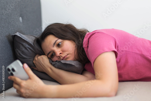 Bilde på lerret A woman lies in bed staring at her phone with a tired, empty expression, smartphone addiction, dopamine dependence, and emotional exhaustion caused by social media comparison and endless scrolling