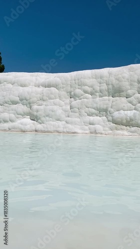 Pamukkale, the cotton castle and cotton hill, white travertine natural hot spring and ancient Roman Greek bath house at Hierapolis ruins site, Turkiye