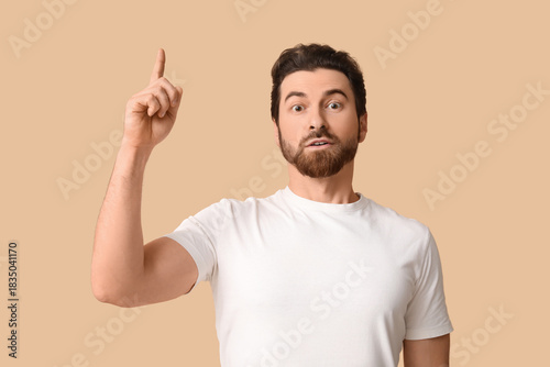 Young man pointing up on be...