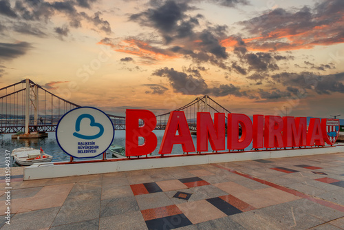 Fototapeta Naklejka Na Ścianę i Meble -  Türkiye - Balıkesir - Bandırma - October 05, 2025: The love bridge on the shore of Bandırma Republic Square at sunset and the name Bandırma.