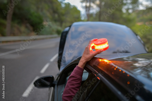 Canvas Print Hand placing V16 emergency safety beacon on a broken down car by roadside, indic