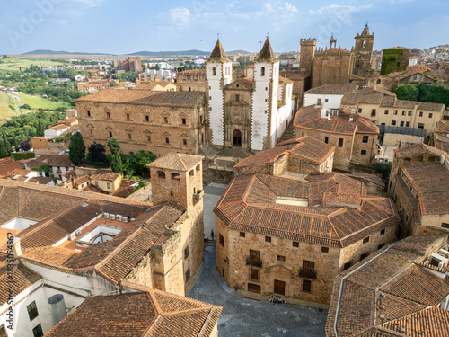 Aerial view of Plaza Santa Maria's ochre rooftops contrasting with the cathedral's white towers piercing the skyline, Cáceres centre old town, Extremadura, Spain.