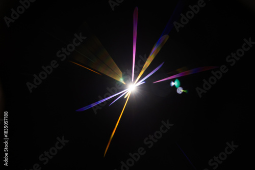 Lens Flare. Light over black background. Easy to add overlay or screen filter over photos. Abstract sun burst with digital lens flare background. Gleams rounded and hexagonal shapes.