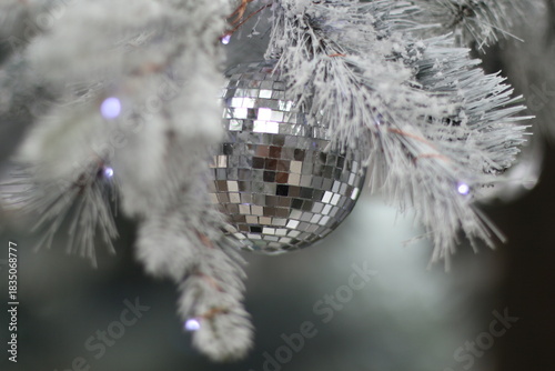 Close-up of a disco ball ornament on a frosted Christmas tree