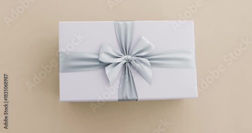 Hands presenting beautifully wrapped white gift box elegant silver satin ribbon offering special present for birthday anniversary or any celebratory occasion Cloud Dancer gray color of 2026 year