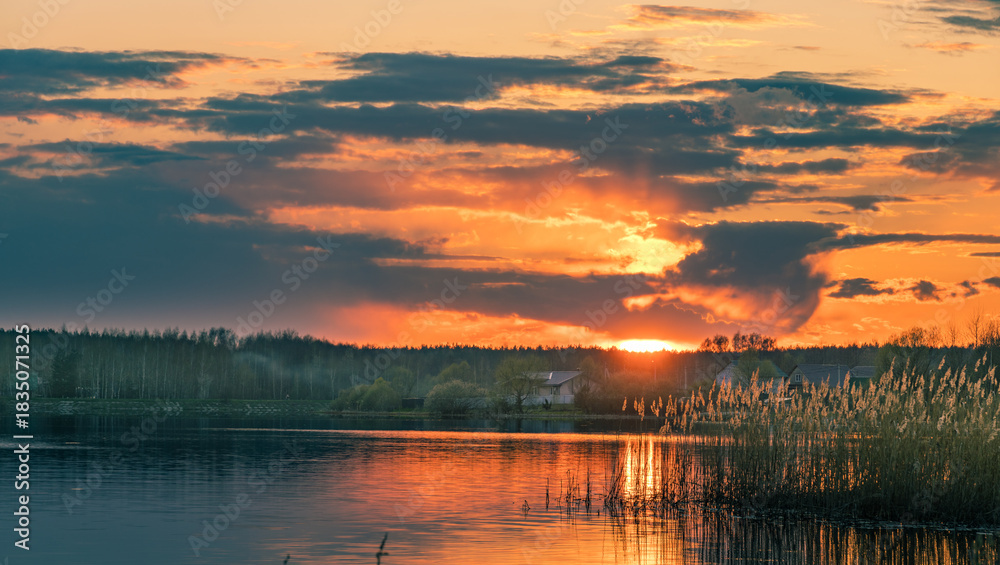 Fototapeta premium Beautiful sunset over a lake with a house in the background