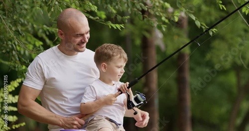 Excitement of man fills air as points to fish swinging from line. Fingers of small boy clutch fishing rod tightly as looks at fish with endless curiosity