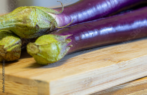Rich purple japanese eggplants on a wooden chopping board